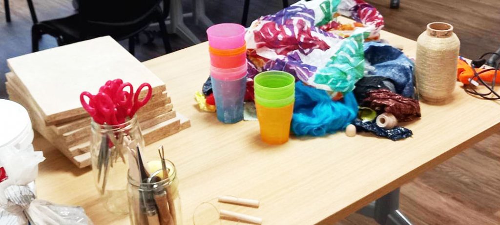 art thérapie à lyon. tissus, papiers colorés, verres et outils. Ciseaux, mirettes, ébauchoirs, fil. Argile. Sur une table.